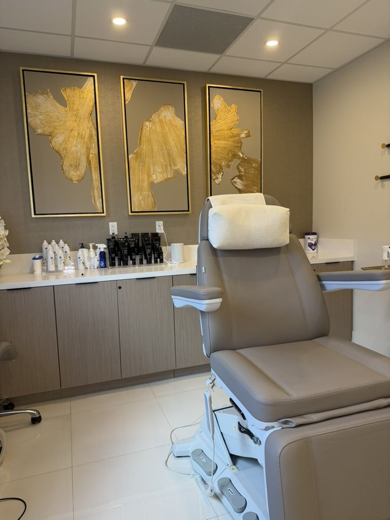 The Glow Suite treatment room, Suite 601, with a treatment chair, product counter and gold abstract paintings