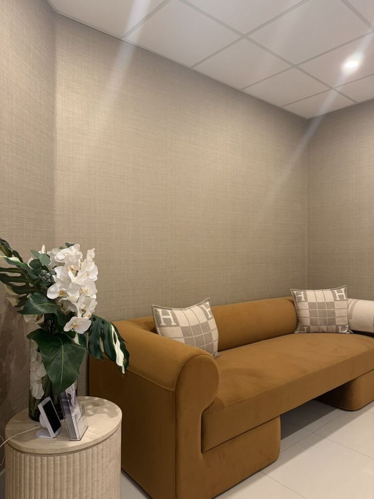 The Glow Suite waiting area, Suite 601, with a caramel velvet sofa and white orchids